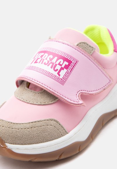 Ροζ και μπεζ παιδικό αθλητικό παπούτσι με λουράκι Velcro, διακοσμημένο με κόκκινο και άσπρο λογότυπο Versace, λευκή σόλα και εσωτερική επένδυση σε νέον κίτρινο χρώμα.