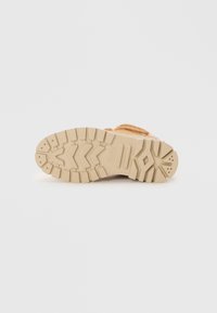 Sole di sneaker marrone chiaro con un motivo di grip testurizzato, caratterizzato da un materiale in gomma spesso e resistente e un battistrada distintivo per la trazione.
