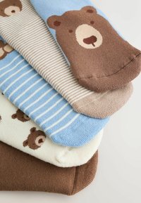 Fire par sokker med bjørnedesign. Farver inkluderer lyseblå, beige, hvid med brune bjørne og mørkebrun. Blød strikket tekstur.