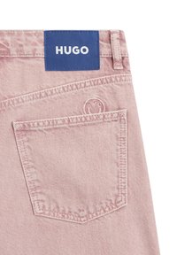 Vaaleanpunaiset farkkushortsit, joissa on sininen, merkitty "HUGO"-tekstillä varustettu kangasmerkki ja takatasku, jossa on hillitty logokirjailu.