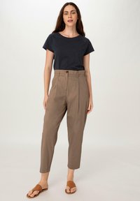 Navy cotton t-shirt with short sleeves, paired with light brown high-waisted pants featuring a front button closure and ankle-length cut. Brown sandals.