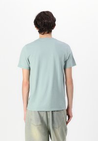 Ανοιχτό μπλε βαμβακερό T-shirt με κοντά μανίκια και στρογγυλή λαιμόκοψη, με απλή πλάτη και χαλαρή εφαρμογή. Συνδυάζεται με ανοιχτόχρωμο τζιν.