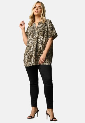 Top corto de estampado de leopardo con escote en forma de ojal, combinado con jeans skinny negros y tacones negros con tiras. Tejido suave con un ajuste holgado.