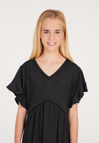 Dunkelgraues Kleid mit kurzen Rüschensäumen, V-Ausschnitt und gerafftem Taillenteil. Verziert mit dekorativen Nähten entlang des Ausschnitts. Glatte Textur.