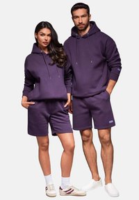 Lila passende Kapuzenpullover und Shorts aus weichem Material. Die Kapuzenpullover verfügen über eine Kordel; die Shorts haben einen elastischen Bund und Taschen. Lässiges Design.