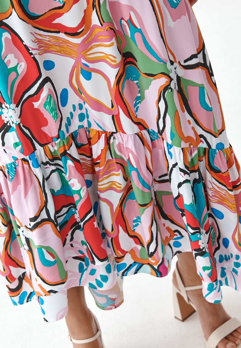 Wielokolorowa sukienka w kwiaty z falbaniastym dołem, wykonana z lekkiego materiału w jaskrawych odcieniach czerwieni, zieleni, różu oraz wyrazistych czarnych konturach.