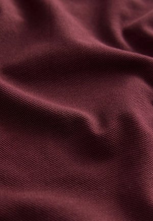 Tissu texturé bourgogne avec des motifs de tissage fins visibles et un drapé doux, capturant une couleur riche et profonde. Idéal pour le revêtement ou les vêtements.
