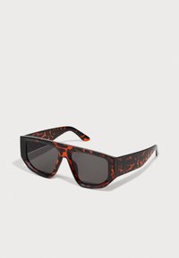 Sonnenbrille mit Schildpatt-Muster und dunklen Gläsern, mit einer auffälligen rechteckigen Form und seitlichen Mustern in Rot und Schwarz.