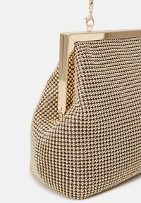 Metaliczna torebka kopertówka z teksturowanym wzorem małych, zaokrąglonych koralików w odcieniach złota i srebra. Posiada elegancką, złotą ramkę i zamek.