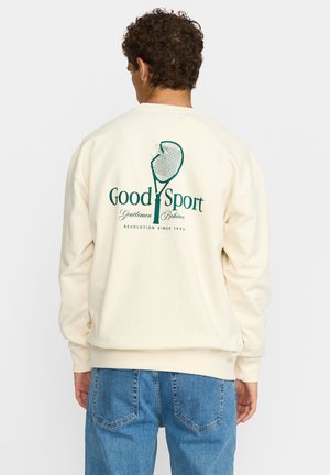 Cremefarbener Sweatshirt mit grünem Grafiktext "Good Sport" und Tennisschläger-Design auf der Rückseite, verfügt über gerippte Bündchen und Saum.