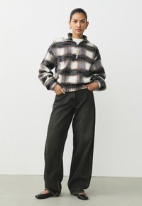 Fleece zip-up pullover i et flerfarvet plaid-design med hvid, navy og burgunder. Sammen med højtaljede, løse sorte denimjeans.