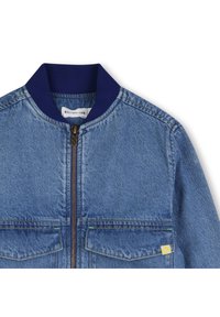 Τζιν μπουφάν με ναυτικό ribbed γιακά, κεντρικό φερμουάρ, δύο τσέπες στο στήθος και κίτρινη ετικέτα διακόσμησης στην κάτω τσέπη.