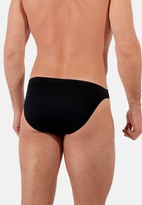 Schwarze Schwimmshorts aus elastischem Material, mit einem tiefen Schnitt und nahtlosem Design an den Kanten für Komfort und eine enge Passform.