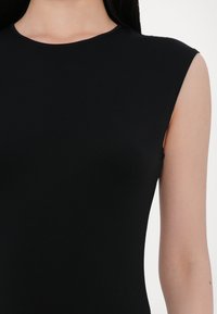 Black sleeveless top with a rounded neckline, made of a smooth, stretchy fabric. Features a close fit and clean finishing at armholes.