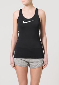 Zwarte mouwloze sporttanktop met een wit Nike-logo, gecombineerd met grijze geprofileerde shorts met een klein wit Nike-logo.