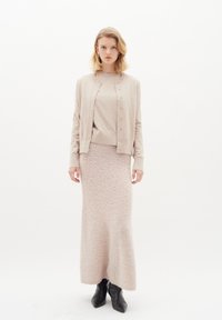 Strickcardigan und passender langer Rock in sanftem Beige mit strukturierter Oberfläche. Der Cardigan hat Knöpfe auf der Vorderseite und lange Ärmel.