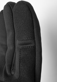 Schwarze Handschuhe mit glatter Textur und gepolstertem Design. Auffällige Nahtdetails und eine enge Passform an den Fingerspitzen.