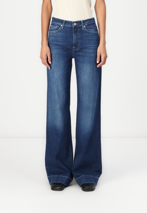 Videben bukse i mørk blå denim, med høy midje, fem lommer og rå kant. Materialet har en glatt tekstur.