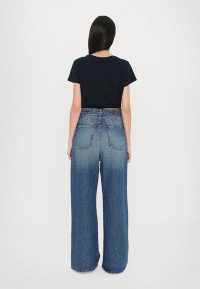 Marineblauwe katoenen T-shirt met korte mouwen, gecombineerd met hooggeprijsde wijde denim jeans in een lichtblauwe gradient, met twee achterzakken.