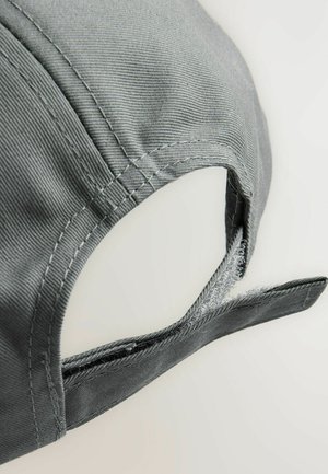 Gorra de béisbol gris con una tela texturizada. Cuenta con una correa ajustable hecha de un material similar, con detalles de costura expuesta.