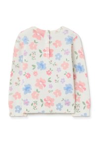 Haut à manches longues à motif floral en crème clair, avec des boutons dans le dos, présentant des fleurs roses, bleues et violettes ainsi que des feuilles vertes.