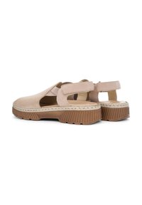 Beige suede slingback shoes with a wide cutout, elastic strap, and textured rubber sole featuring ridges and a woven jute accent.