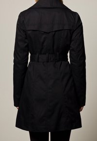 Czarny trenchcoat z paskiem w talii, dużym kołnierzem i rozcięciem z tyłu. Wykonany z gładkiego, trwałego materiału o dopasowanej sylwetce.