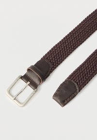 Καφέ υφασμάτινη ζώνη πλεγμένη με σκούρες καφέ δερμάτινες άκρες και ασημένια μεταλλική αγκράφα πάνω σε λευκό φόντο.