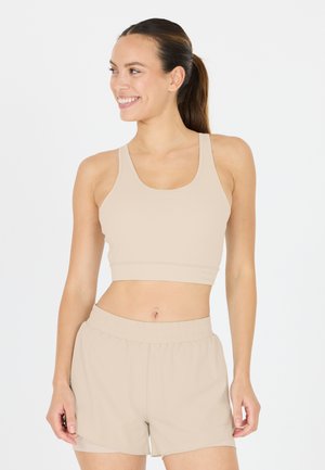 Beige sportbeha met een brede, platte band en dikke bandjes, gecombineerd met bijpassende lichtgewicht shorts met een elastische tailleband.