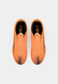 Scarpe da ginnastica arancioni con tomaia testurizzata, dettagli neri e design aerodinamico. Presentano lacci e un logo sulla linguetta.