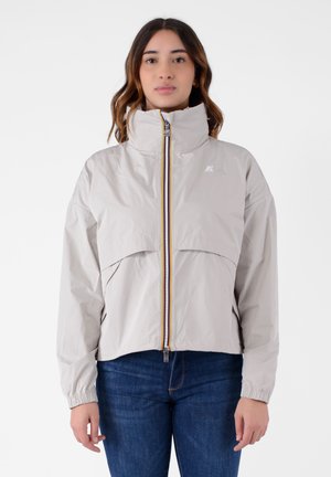 Giacca zip-up beige chiaro con colletto alto e polsini elasticizzati, dotata di una tasca frontale e dettagli sulla cerniera multicolore.
