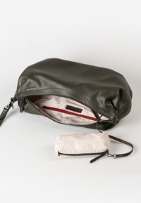 Pochette da polso in pelle verde scuro con interno in tessuto a motivo chiaro e una piccola pochette con zip abbinata attaccata tramite una cinghia.