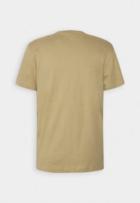 T-shirt beige uni à manches courtes vu de dos sur fond blanc.