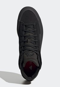 Černá sportovní bota s texturovaným textilním svrškem, plochými tkaničkami a gumovou podrážkou. Ikonické logo značky viditelné na jazyku boty. Minimalistický design.