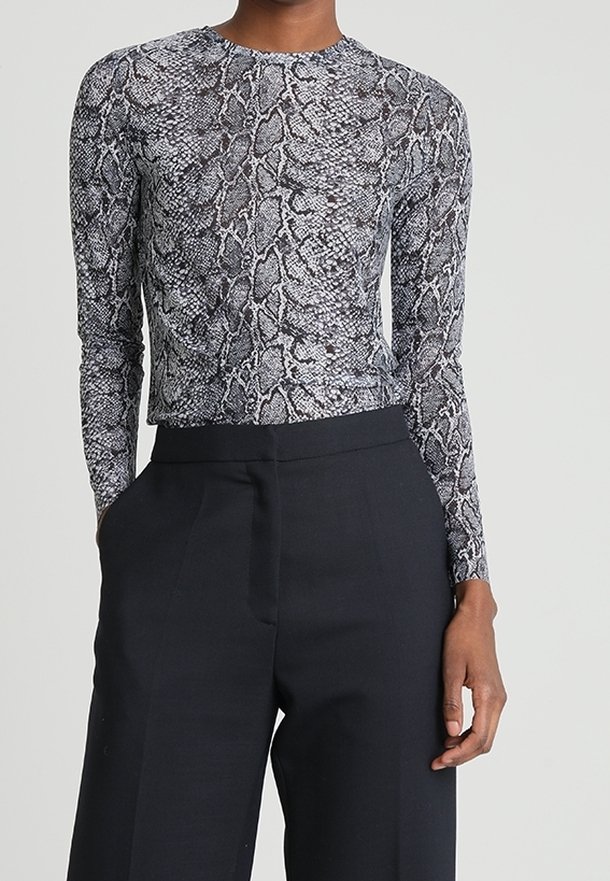 Langarmshirt mit einem schwarzen und grauen Schlangenprint. Hergestellt aus einem figurbetonten, dehnbaren Material, kombiniert mit hoch taillierten Hosen.