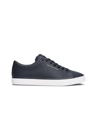 Baskets basses bleu marine avec lacets noirs, semelle blanche et logo Tommy Hilfiger sur le côté et la languette, présentées sur fond blanc.