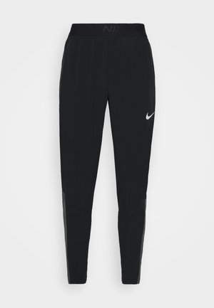 Schwarze Nike-Sporthose mit zulaufenden Beinen und weißem Swoosh-Logo am oberen linken Oberschenkel, elastischer Bund mit dezentem Nike-Branding.