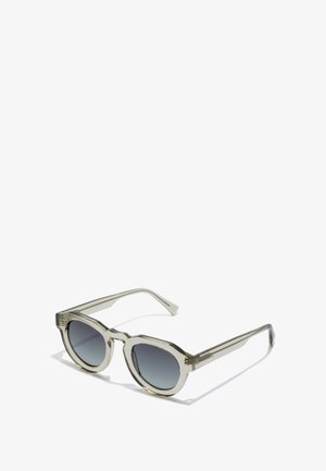 Läbipaistvad oliivrohelised prillid ümarate raamidega, gradient hallide läätsede ja stiilsete, sujuvate kätega. Raamil on silmapaistvad aktsendid.