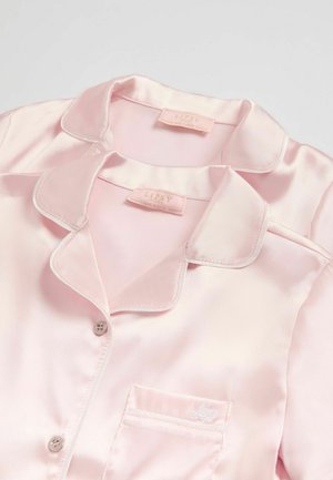 Vaaleanpunainen satiininen pyjama-setti, jossa on kaulus, nappisuljenta ja pieni brodeerattu logo rintataskussa; sileä pinta ja kiiltävä viimeistely.