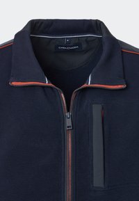 Marineblaue Zip-up-Jacke aus strukturiertem Stoff, mit kontrastierenden roten Reißverschlussakzenten und einem hohen Kragen. Verfügt über ein markiertes Innenetikett.