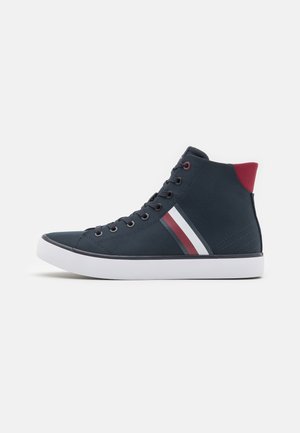 Basket montante bleu marine avec semelle blanche, patch rouge au talon et bandes latérales rouge, blanc et bleu, vue de côté extérieur.
