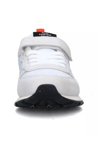 Scarpa sportiva bianca con parte superiore liscia e fascia in velcro; presenta una soletta nera e un'etichetta "CORRI PIÙ VELOCE DI" in nero e rosso sul tallone.
