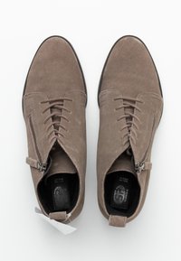 Stivaletti alla caviglia in camoscio grigio con una texture liscia, chiusura anteriore con lacci, cerniera laterale e punta arrotondata. Solette nere visibili all'interno.