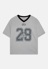 Pelēks īsām piedurknēm t-krekls, kas izgatavots no kokvilnas ar melnu V-veida kaklu. Satur pelēko "GAP" logotipu un lielo "28" kopā ar Mickey Mouse grafiku.