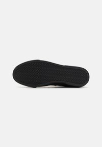 Black sneaker sole with a herringbone tread pattern, made from rubber. The design features smooth edges and a slightly raised heel.