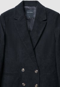 Dunkelblazer aus Cord mit Reverskragen, doppelter Knopfleiste und zwei Fronttaschen. Etikett innen sichtbar. Größe S.