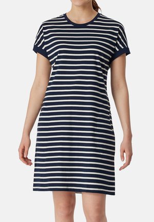 Frau trägt ein kurzärmeliges Kleid mit navyblauen und weißen horizontalen Streifen und rundem Ausschnitt vor einfarbigem Hintergrund.