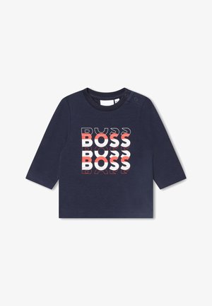 Chemise à manches longues bleu marine pour tout-petit avec le mot "BOSS" répété trois fois en texte blanc et rouge sur le devant, et des boutons-pression sur une épaule.