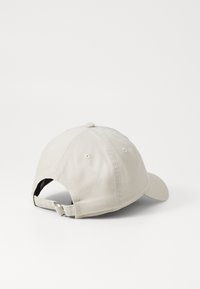 Beige bomull-baseballcap med buet brem, justerbar stropp bak og seks ventilasjonsøyler på kronen.