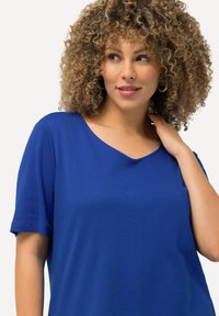 Blauw T-shirt met korte mouwen, voorzien van een V-hals en zachte textuur. De stof lijkt glad met een lichte glans en heeft een ontspannen pasvorm.
